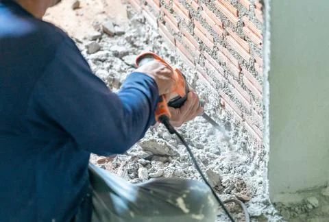 Worker drilling wall with an electric drill. Stock Photos