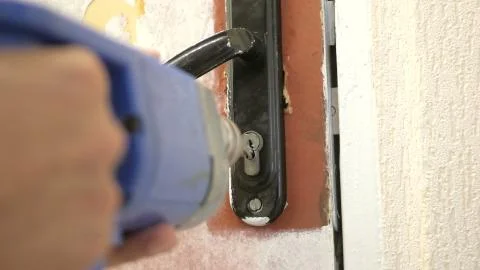 The worker drills the door lock Stock Photos