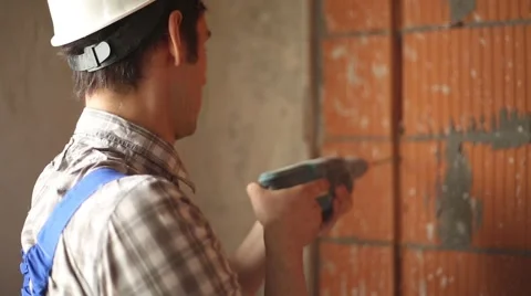 Worker drills hole in wall Stock Footage 61695199