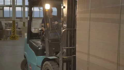 Worker drives forklift loader carrying stack of folded boxes Stock Footage 145543871