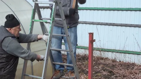 A worker drives an iron pole into the ground with a sledgehammer. Stockbeeldmateriaal 157286720