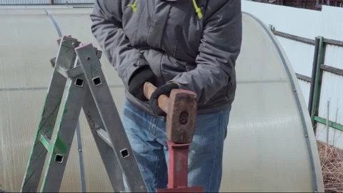 A worker drives an iron pole into the ground with a sledgehammer. Video stock 157286741