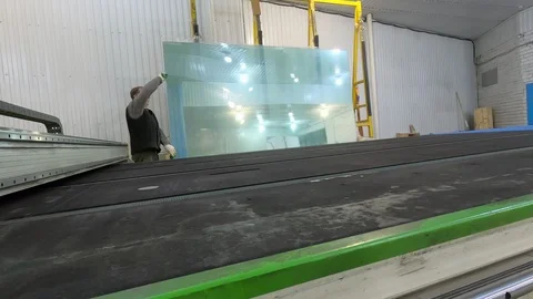 A worker drops a sheet of glass from the counter and pushes it across the table. Video stock 124605454