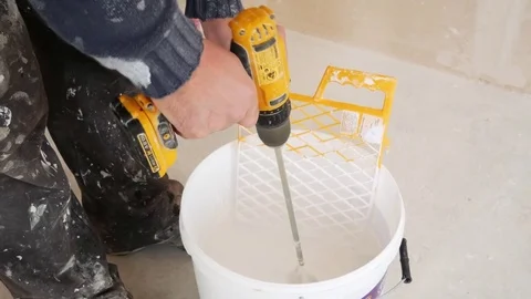 The worker with electric drill mixes the paint in a bucket Stock Footage 84885688