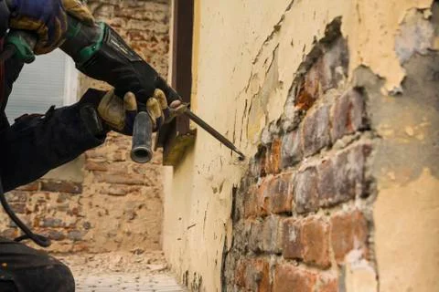 Worker with electrical hammer cleaning red brick wall outdoor Stock Photos