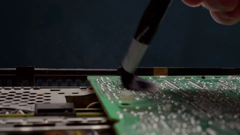 Worker in an electronics service center removes dust from an old large chip Stock Footage 219670398