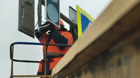 Worker in the elevator cradle fixes the LED traffic light. Road sign. LED Stock Footage 141087606