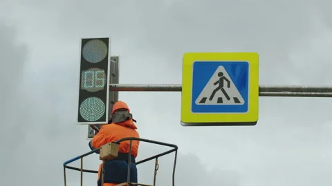 A worker in an elevator cradle repairs an LED traffic light. Road sign. LED Stock Footage 141077886