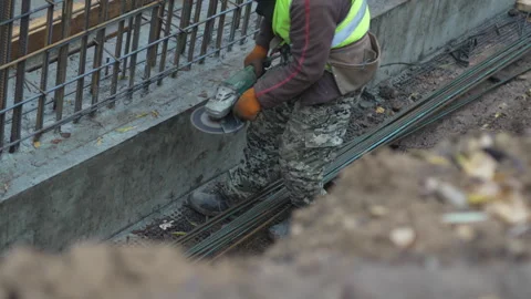 Worker engaged in grinding rebar within concrete foundation Видео 311108025