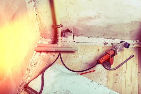 Worker engaged in home improvement project using equipment to cut pipes on .. Stock Photos
