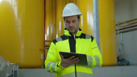 Worker engineer man working tablet computer on tubing of pump system at offshore Stock Footage 156232093