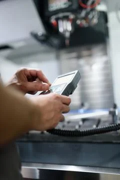 Worker entering data in CNC machine at factory floor to get the production go Stock Photos