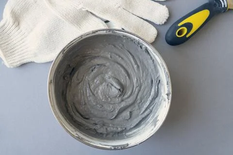 Worker equipment: container with cement, putty knife and workers gloves Stock Photos