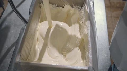 Worker is evenly spreading the poured ice cream inside of the box with a spatula Stock Footage 201829519