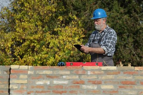 Worker examining brick wall 库存照片