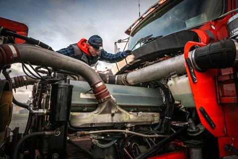 Worker examining the engine of a red semi truck Stock-Fotos