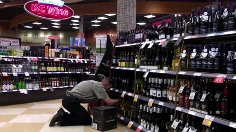 Worker exhibiting wine on the display rack inside BC liquor store Stock Footage 64301888