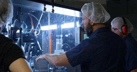 Worker explaining machine operations to other factory workers Stock-Footage 104000555