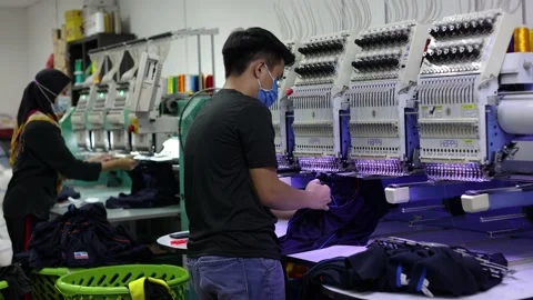 Worker with face mask cutting thread on staff uniform on Garment Manufacturer Stock Footage 171520925