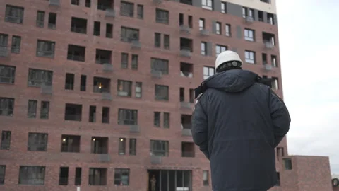 Worker faces brick facade reflecting light on job site Видео 313829360
