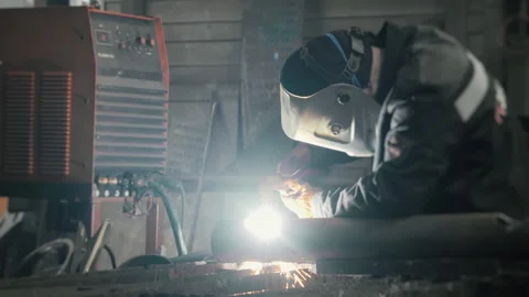 A worker in a factory cuts a hole in a iron pipe with a plasma cutter. Video stock 306540261
