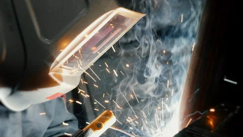 A worker at a factory in a protective mask welds a metal structure. Video stock 306540863
