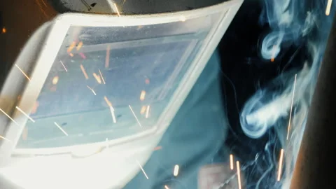 A worker at a factory in a protective mask welds a metal structure. Video stock 306541477