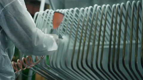 Worker at the factory using a spray gun paints metal pipes with special paint Stock Footage 115935134