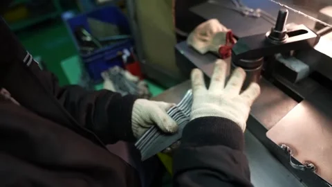 Worker fans a stack of shiny scissor blades in gloved hands beside a polishing Stock Footage 346737898