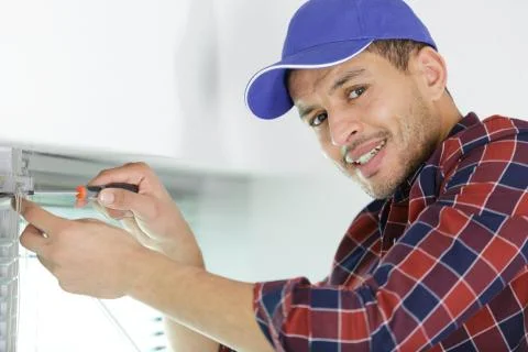Worker fasten the handle to a plastic window Stock Photos
