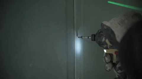 Worker fastening drywall panel with screw using drill Stock Footage 314058545