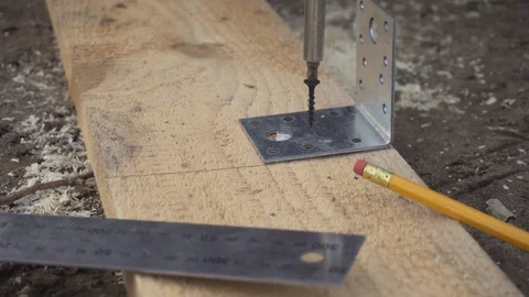 Worker fastens a metal corner to the plank with screws. Fixing wooden boards. Stock Footage 129780088