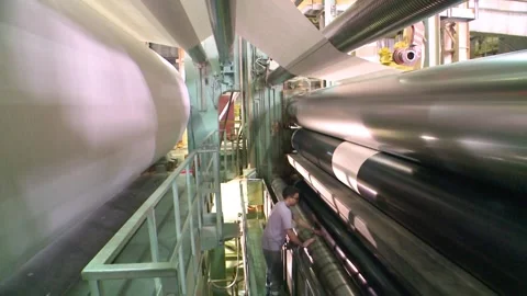 A worker feeds paper into a paper making machine. Paper production Stockbeeldmateriaal 267402204