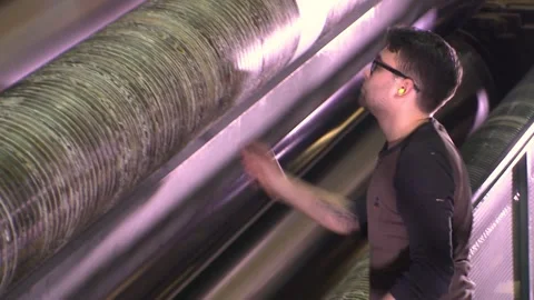 A worker feeds paper into a paper making machine. Paper production. Video stock 267402425