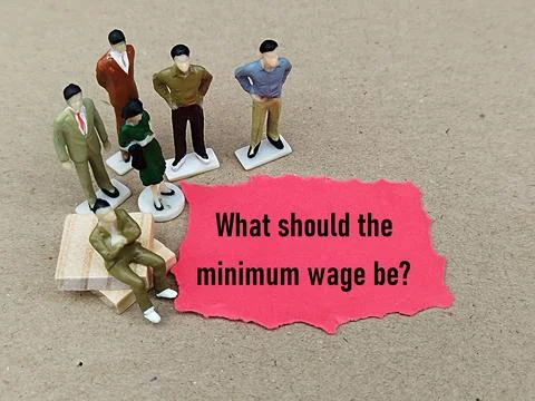 Worker figure with torn paper written What should the minimum wage be Foto stock