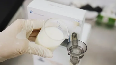 Worker fills testing equipment cup with fresh milk in lab 스톡 동영상 124582011