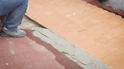 Worker finishing mortar edge beside flat clay roof tiles Stock-Footage 345695196
