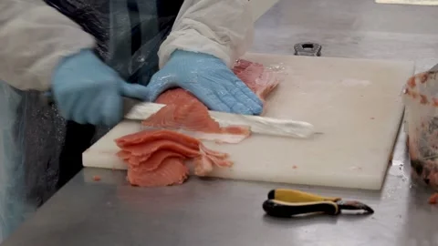 A worker at a fish processing plant cuts meat into pieces with a knife Stock Footage 318471340