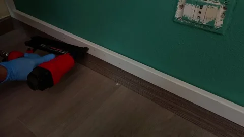 Worker fixes a board to a wall using a nail gun. Building works, DIY, home Stock Footage 267250352