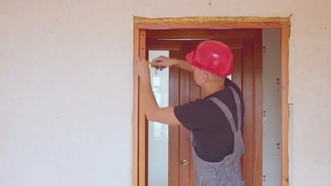 The worker fixes or repairs the interior door removes measurements, with a Video stock 101173856