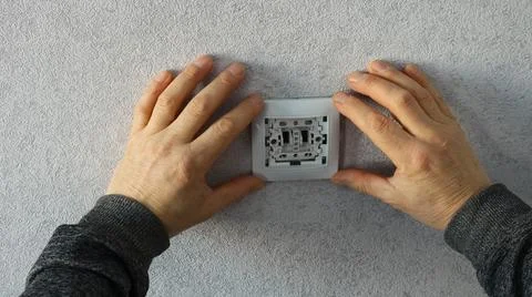 The worker fixes the outlet or light switch by attaching the frame Stock Photos