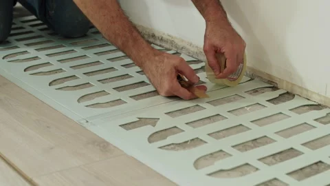 Worker Fixing Foam Underlayment Sheets with Adhesive Tape Stock Footage 322054750