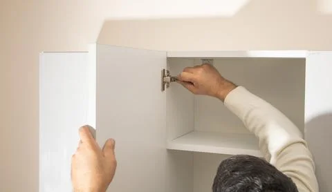 Worker fixing kitchen cabinet using screwdriver. Stock Photos