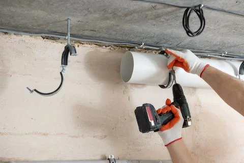 A worker is fixing ventilation pipes. Stock Photos