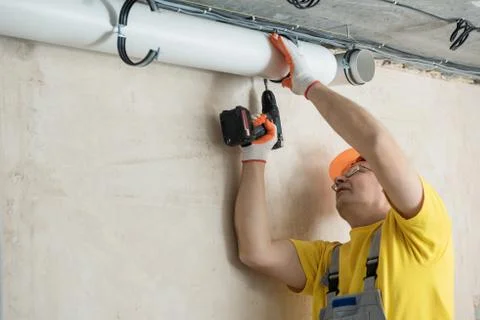 The worker is fixing ventilation pipes. Stock Photos