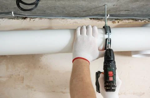 A worker is fixing ventilation pipes. Stock Photos
