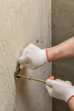A worker is fixing up a wall of bolts. Stock Photos