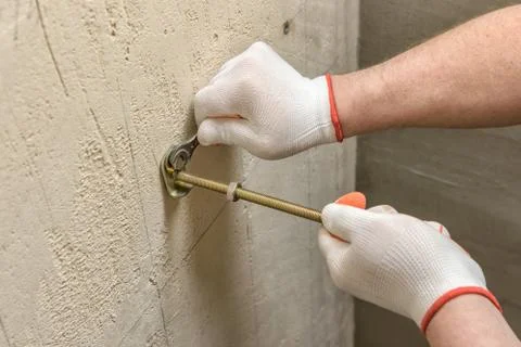 A worker is fixing up a wall of bolts. Stock Photos