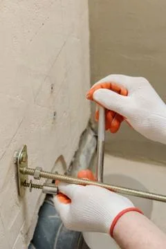 A worker is fixing up a wall of bolts. Stock Photos