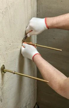 A worker is fixing up a wall of bolts. Stock Photos